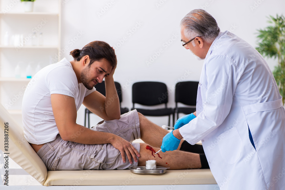 Fototapeta premium Leg injured man visiting old doctor in first aid concept