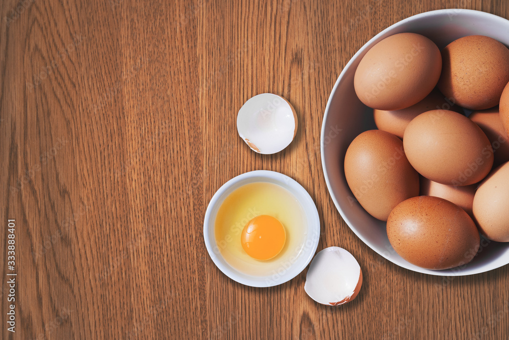 Chicken eggs with egg yolk in a bowl on wood table top view. Copy space is provided. Chicken eggs with egg yolk in a bowl on wood table top view. Copy space is provided.