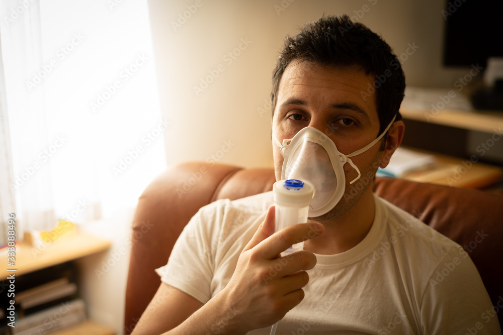 COVID-19 Pandemic Coronavirus; Close-up of young man using respirator machine for breathing at home. man using CPAP machine and wearing nasal mask