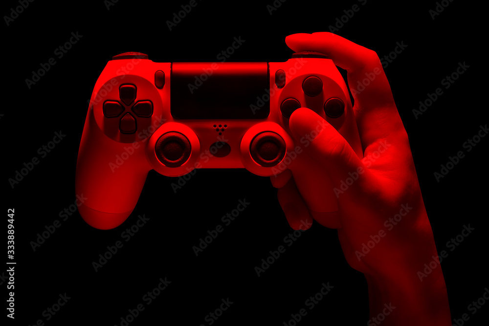 Hyman hand holding white video game gamepad in neon lights isolated on a black Hyman hand holding white video game gamepad in neon lights isolated on a black
