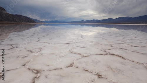 Flying over over mirror surface of salt crust formations with water in Badwater Basin, Death Valley National Park. California, USA.