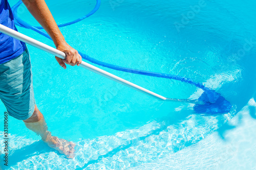 swimming pool cleaning. a man is cleaning the pool. service care