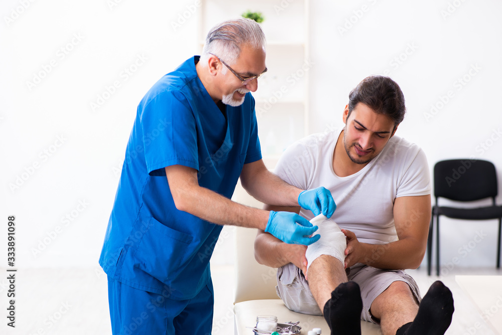 Obraz premium Leg injured man visiting old doctor in first aid concept