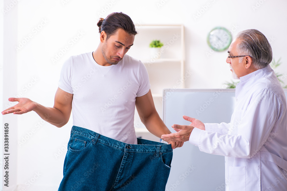 Fototapeta premium Doctor dietician and happy patient wearing large trousers
