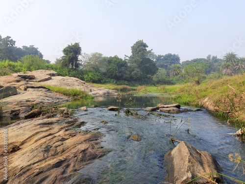 River water flowing through stones and rocks at dawn.Mountain river flows through green forest.Tropical river in the rain forest in Asia.Wild river flowing through the mountain.