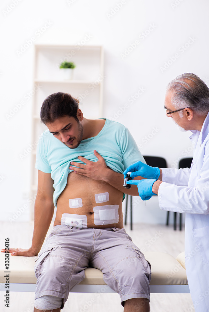 Fototapeta premium Injured young man visiting experienced male doctor