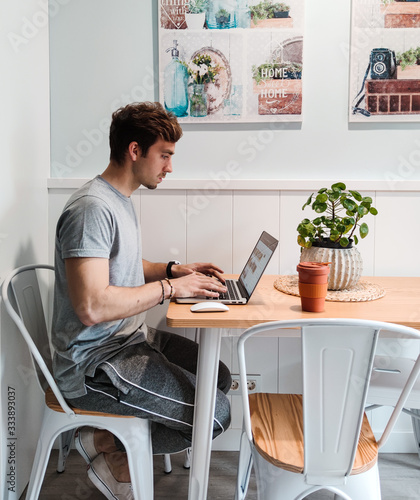 Chico joven trabajando con ordenador portátil en casa 