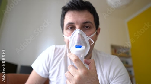COVID-19 Pandemic Coronavirus; Close-up of young man using respirator machine for breathing at home. man using CPAP machine and wearing nasal mask