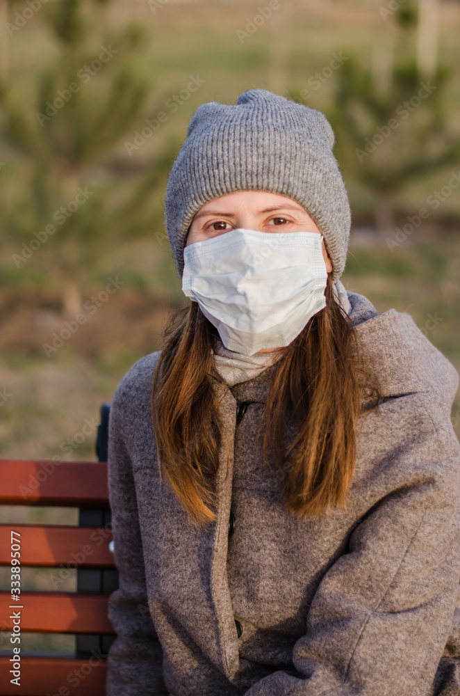 A young woman walking in the park in a medical mask.. Coronavirus protective mask. Covid-19 A young woman walking in the park in a medical mask.. Coronavirus protective mask. Covid-19