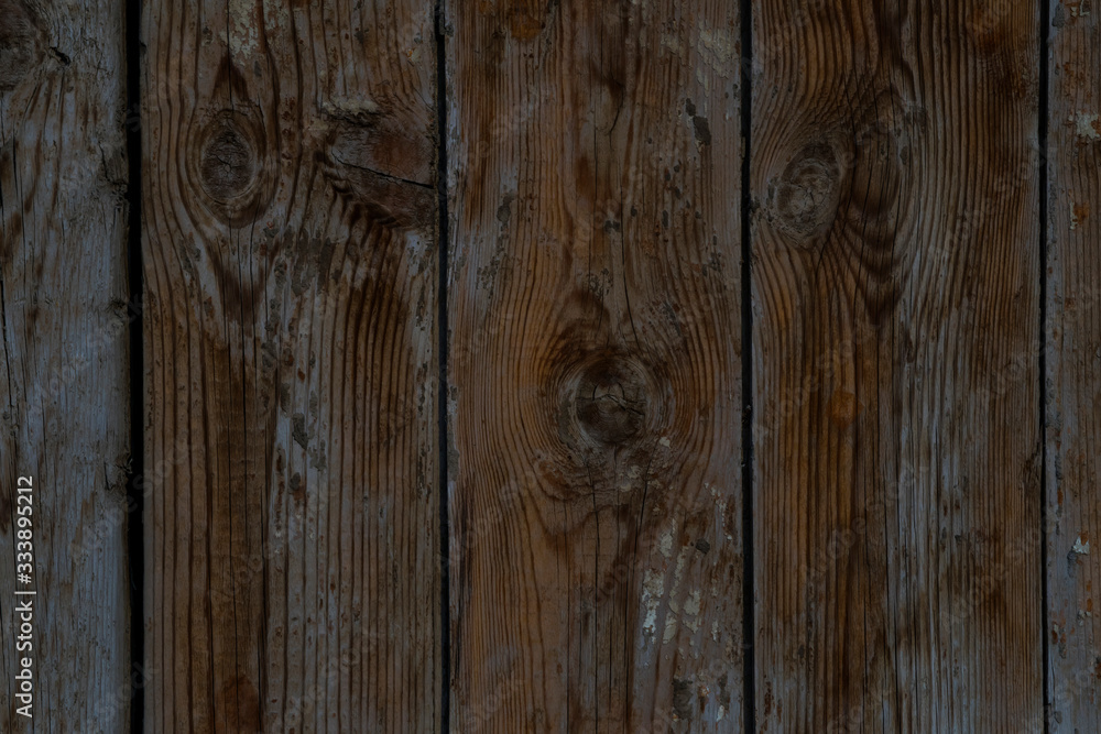 Naklejka premium Wooden boards. Grunge texture of wooden boards. Abstract wooden background. The rough texture of the raw wood. Old fence made of wooden boards. Deep cracks. Remains of old paint on the boards