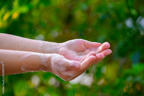 Mother and child washing hands with soap and water on green blur background. © Nutt
