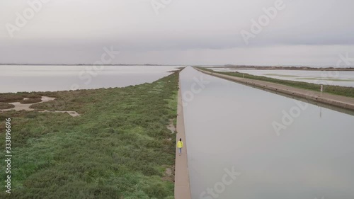 Homme marchant le long d'un fleuve par temps nuageux