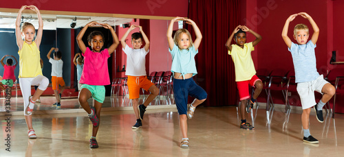 Smiling little boys and girls hands up in class