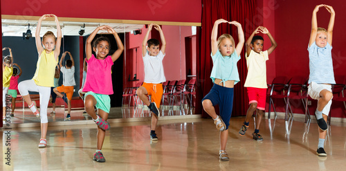 Childrens trying balance movements of ballet in classroom