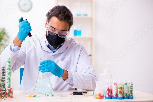 Young male chemist in drug synthesis concept photo