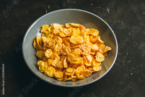 Tasty crispy corn flakes in bowl on the rustic background. Selective focus. Shallow depth of field.