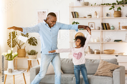 Stay at home leisure. Senior African American man dancing with his granddaughter indoors