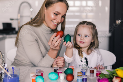 Loving mother and her daughter have fun with painting easter eggs. Cozy home atmosphere. Easter.