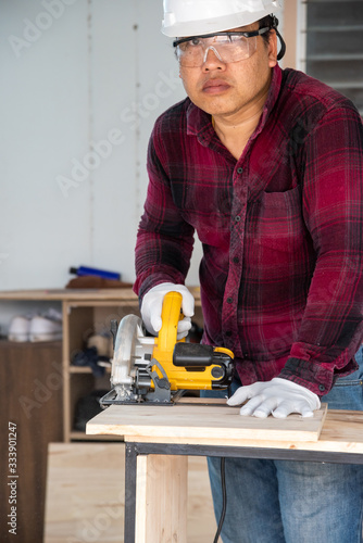 Worker cutting wood with power saw  