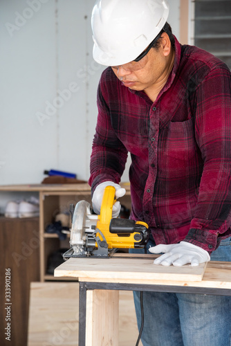 Worker cutting wood with power saw  