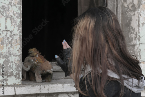 Teenager girl with an old plush toy on the background of an abandoned and destroyed building. Consequences of COVID-19 Coronavirus protection. After a pandemic