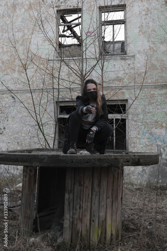 Teenager girl in a black medical mask, on the background of an abandoned post-apocalyptic building. Consequences of COVID-19 Coronavirus protection. After a pandemic