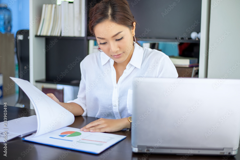 Beautiful Asian business women checking document and using notebook for working at home Beautiful Asian business women checking document and using notebook for working at home