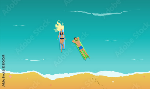 A young pretty blonde girl swims in the sea on the air mattress. A young handsome man swims on the inflatable mattress. View from above. A couple is on a summer vacation. Youth sunbathes in the water.