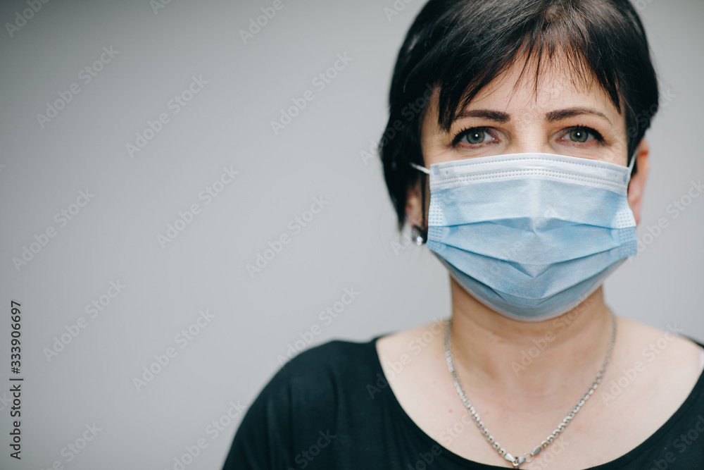 Senior Woman Takes on Medical Mask. Breathes deeply and looking at camera on grey background. Health care and medical concept. Senior Woman Takes on Medical Mask. Breathes deeply and looking at camera on grey background. Health care and medical concept.