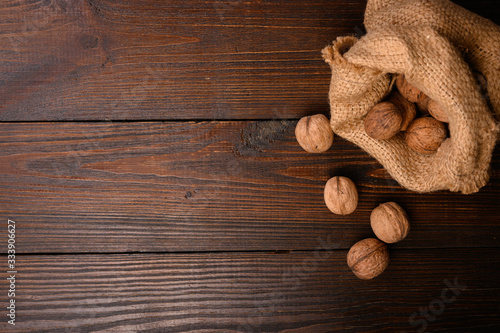 scattered walnuts in a canvas bag on a wooden background