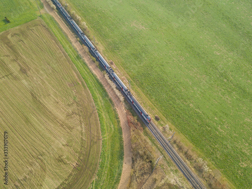 Aerial view of Swiss commuter train. Railroad tracks through agricultural farmland and fields.