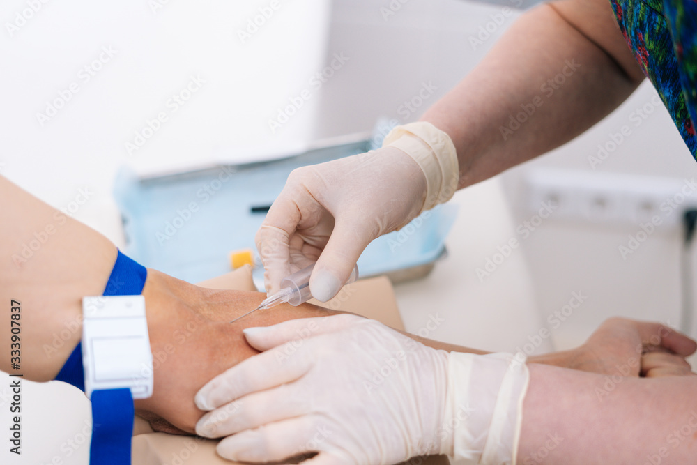 Close-up of hand of man giving blood for biochemical blood testing. Phlebotomist technician drawing blood for testing Coronavirus COVID-19 disease infestation. Concept of healthcare and medicine.