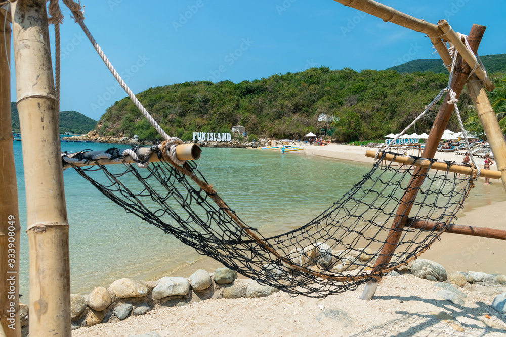 Obraz premium Bamboo hammock on a sandy beach and green hills in the tropics