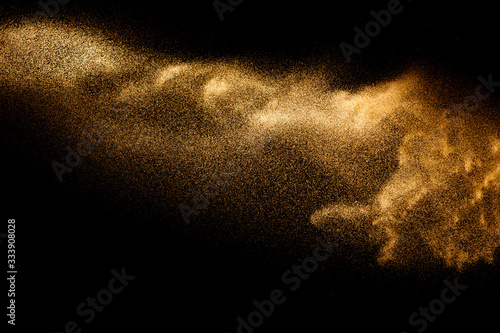 Golden sand explosion isolated on black background. Abstract sand cloud.Sandy fly wave in the air. photo