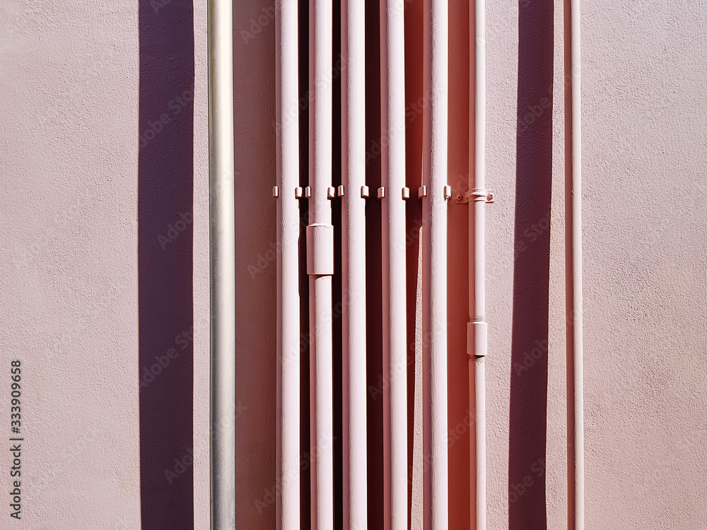 Set of Pink Vertical Water Piping Against Pink Wall Set of Pink Vertical Water Piping Against Pink Wall