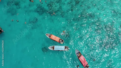 Aerial frone fly by the Tropical paradise Mnemba Island, located 3 km off the coast of Zanzibar's main island Unguja. Lent of Dhow Boats with divers came for snorkeling tour photo