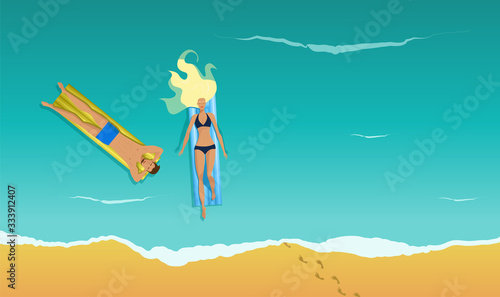 A young pretty blonde girl swims in the sea on the air mattress. A young handsome man swims on the inflatable mattress. View from above. A couple is on a summer vacation. Youth sunbathes in the water.