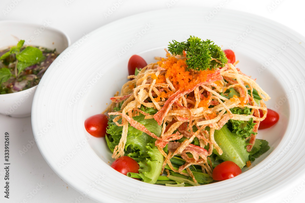 crab salad (fried imitation crab) vegetable and tomato top with shrimp eggs (tobiko) and parsley eat with thai spicy sauce serve in white dish