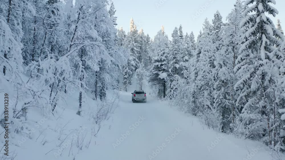 Aerial drone shot of a road immersed in the Lapland forest during the winter with a white SUV. Aerial drone shot of a road immersed in the Lapland forest during the winter with a white SUV.
