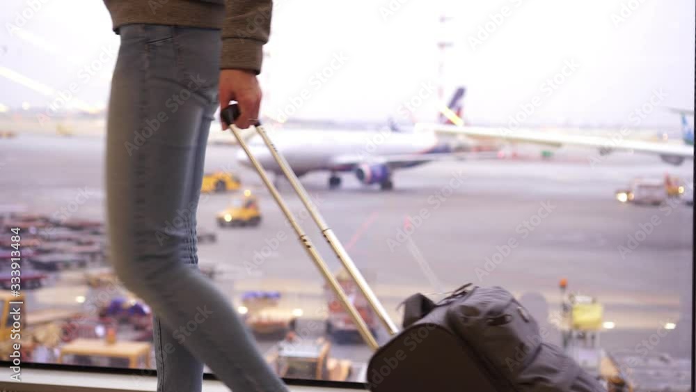 A woman is walking with a suitcase at the airport terminal A woman is walking with a suitcase at the airport terminal