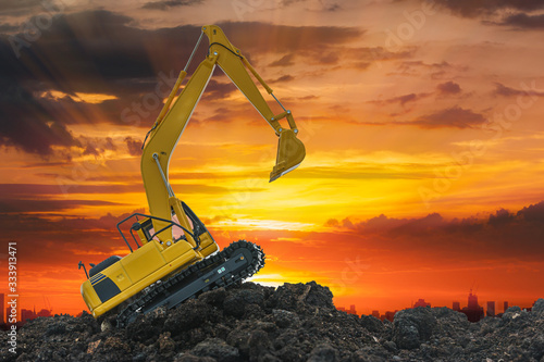 Excavators are digging the soil in the construction site on the sunset background