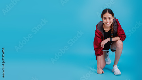 Portrait of confident beautiful asian fitness woman smiling and warm up before exercise isolated on blue color background with copy space.Concept of slim and healthy happy girl workout.