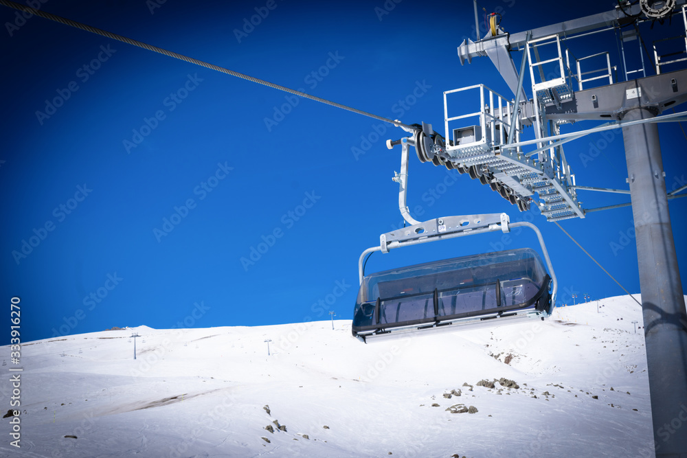 Obraz premium Empty chair lift and holding contructions with snowy peak in the background. Ski resort end season 2020. Gudauri. Georgia