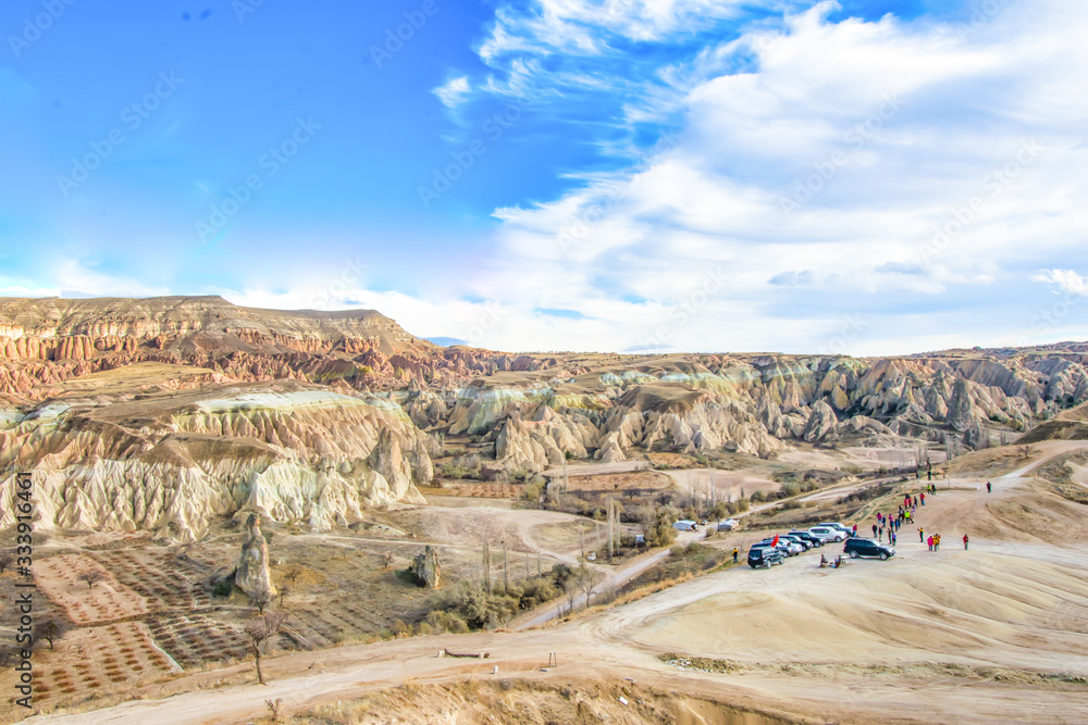 Many tourists standing in a view point with tour jeeps around by the canyon in Cappadocia. Tourism  and activities in Turkey.