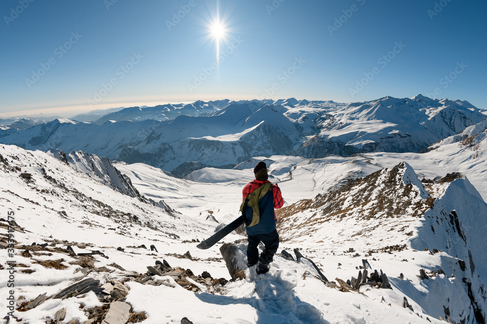 snowboarder looks down at snow-capped peaks of mountains.
