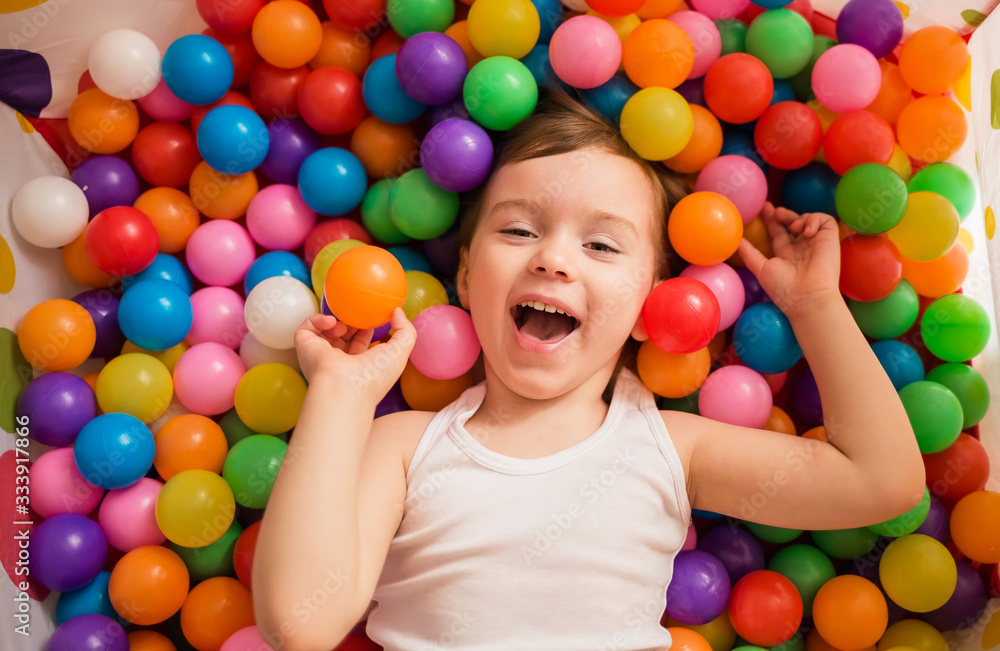 Little girl lies in multicolored balls Little girl lies in multicolored balls