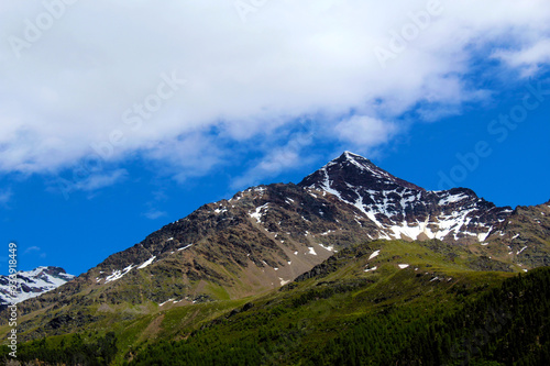 Muntain in early summer covered by forest and little snow on the top