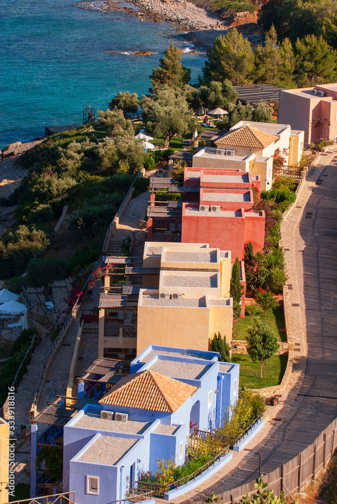 Fototapeta premium Multicolored houses with gardens, roofs and terraces by the sea near Agios Nikolaos on the island of Crete in the Aegean sea, Greece, Europe.