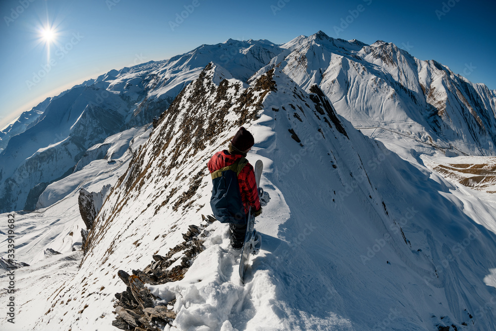 one snowboarder with backpack stands on top of mountain.