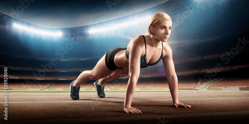 Fit, athletic woman on a sports stadium does push-ups
